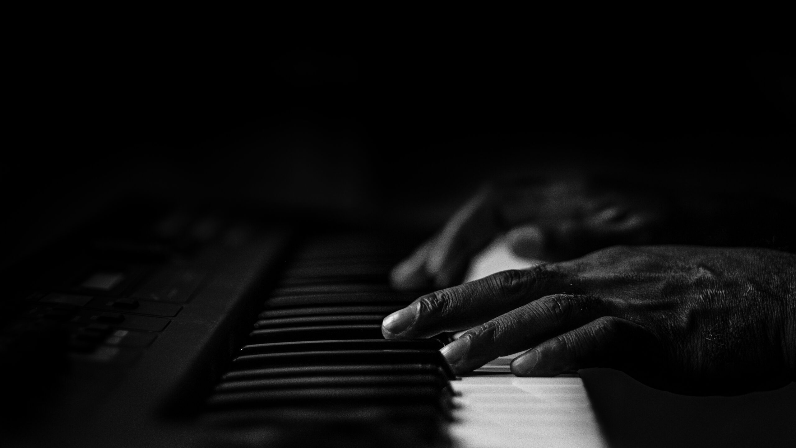 Old wrinkled hands on a piano in black and white