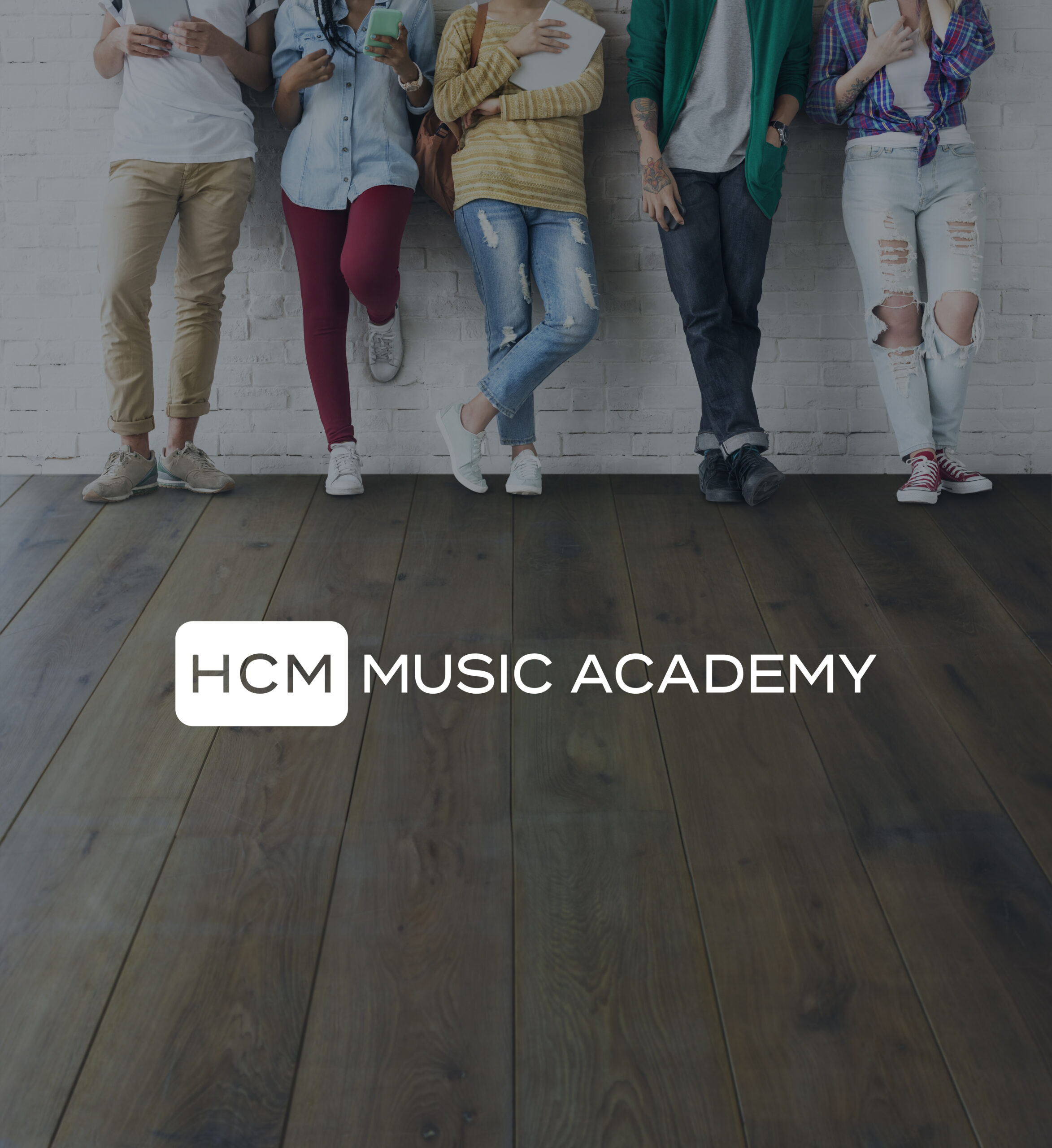 HCM logo on the floor whilst students stand behind against a wall.